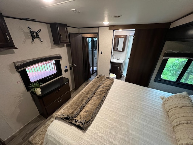 bedroom featuring ensuite bathroom, sink, and light hardwood / wood-style floors