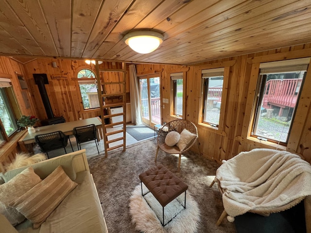 living room with wood ceiling, a wood stove, lofted ceiling, wood walls, and carpet floors