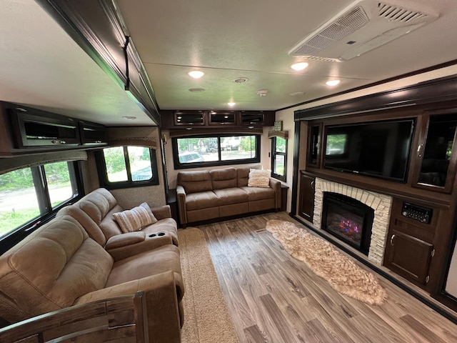 living room with a stone fireplace, visible vents, and wood finished floors