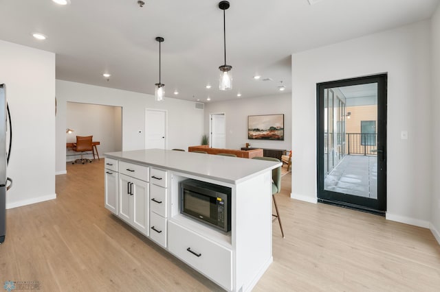 kitchen featuring white cabinetry, a center island, light hardwood / wood-style floors, and pendant lighting