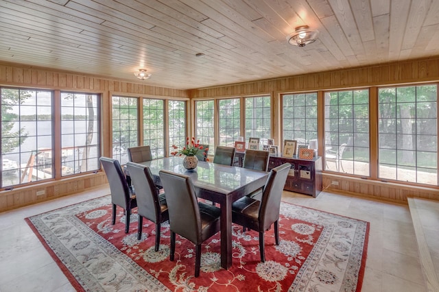 tiled dining space featuring wood ceiling and wood walls