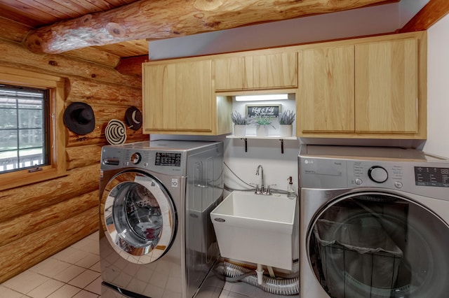 laundry area featuring rustic walls, light tile patterned flooring, washing machine and dryer, cabinets, and sink