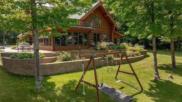 view of playground featuring a yard, a patio, and a sunroom