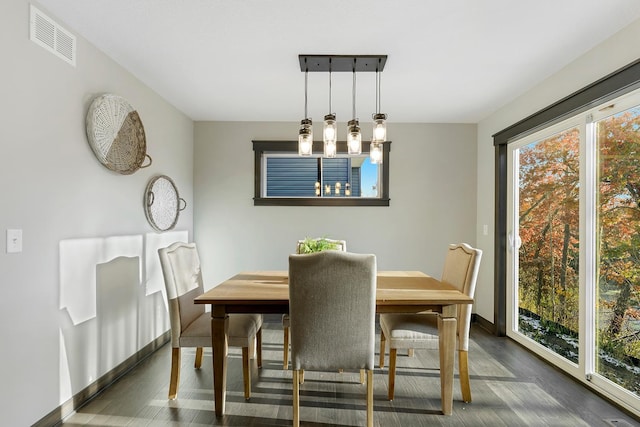 dining area with dark wood-type flooring and a notable chandelier