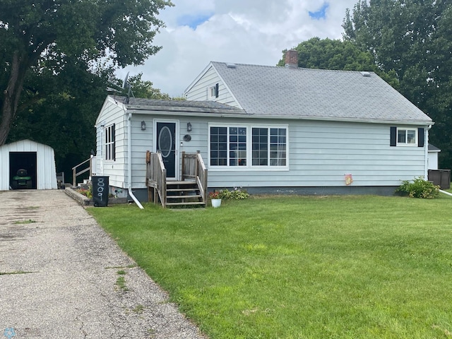 view of front of property featuring a garage, an outdoor structure, and a front lawn