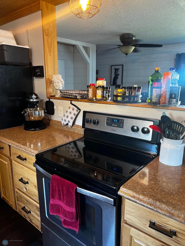 kitchen featuring wooden walls, black electric range, ceiling fan, and a textured ceiling