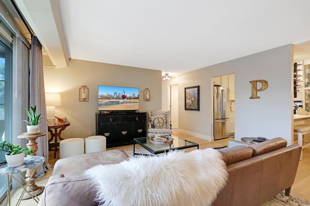 living room featuring beamed ceiling and light hardwood / wood-style floors