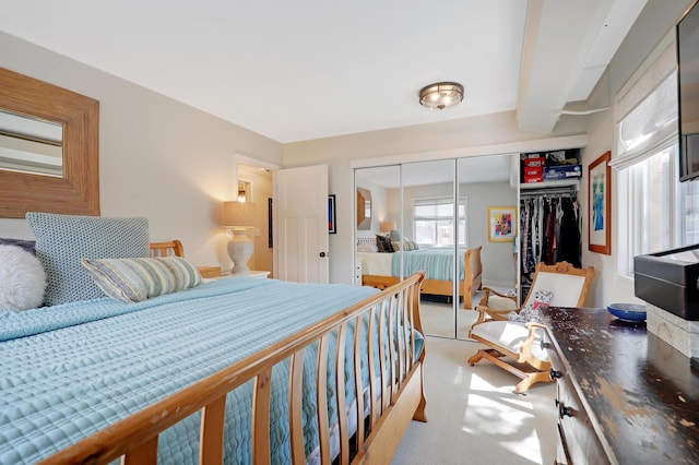 carpeted bedroom featuring a closet and beamed ceiling