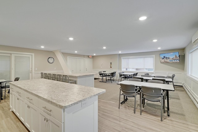 kitchen featuring plenty of natural light, light hardwood / wood-style floors, white cabinets, and a center island