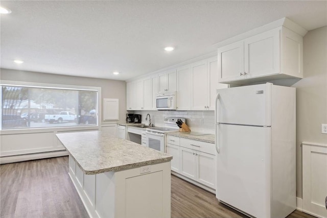 kitchen featuring hardwood / wood-style floors, a baseboard heating unit, white appliances, white cabinets, and a center island