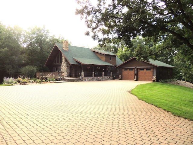 cabin with a garage, an outbuilding, and a front lawn