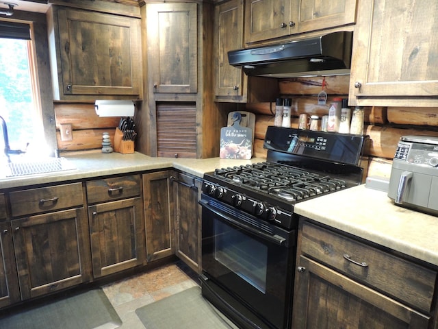 kitchen with black gas range oven, dark brown cabinetry, and sink