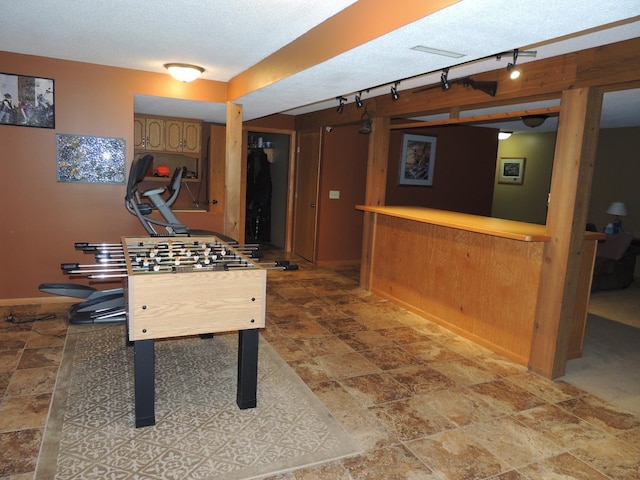 20578 317th St, Farming Twp, MN 56310 - recreation room featuring a bar, a textured ceiling, baseboards, stone finish flooring, and track lighting