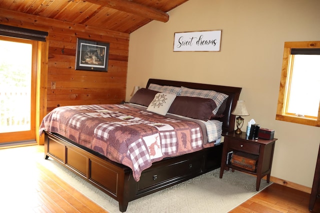 bedroom with lofted ceiling with beams, wood walls, wooden ceiling, and light hardwood / wood-style floors