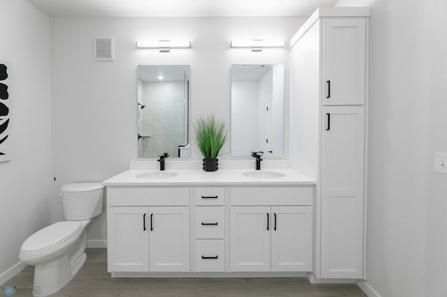 bathroom with toilet, vanity, and a shower with shower door