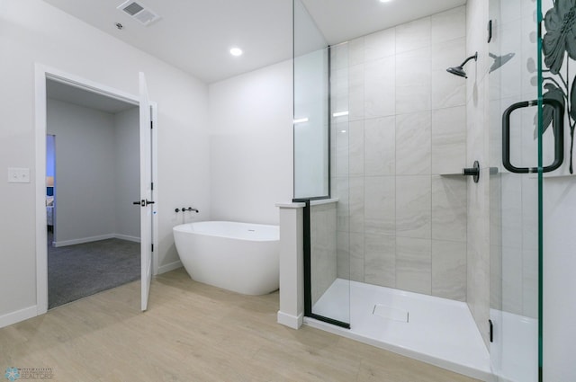 bathroom featuring wood-type flooring and separate shower and tub