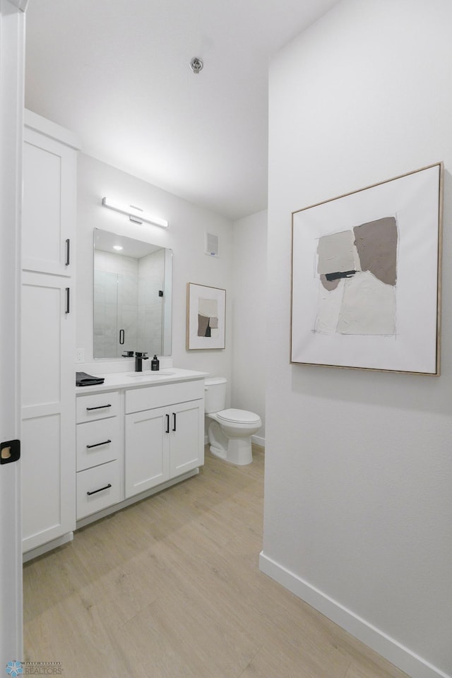 bathroom featuring vanity, toilet, a shower with door, and hardwood / wood-style floors