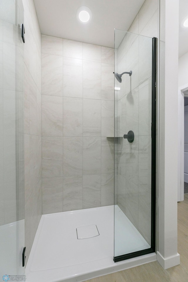 bathroom with wood-type flooring and tiled shower