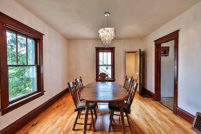 dining space featuring light wood-type flooring, plenty of natural light, and an inviting chandelier