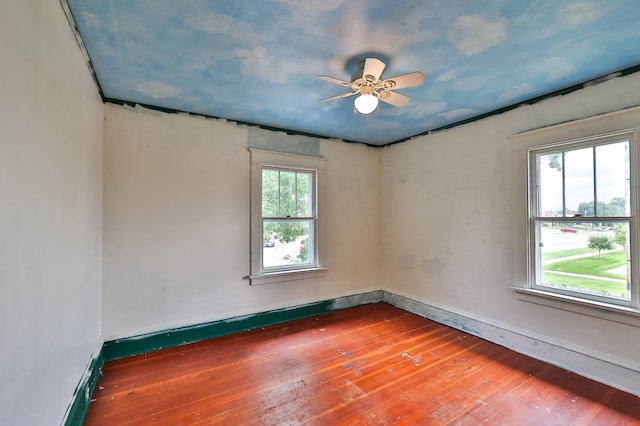 spare room featuring a healthy amount of sunlight, wood-type flooring, and ceiling fan