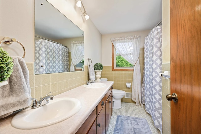 bathroom featuring backsplash, dual vanity, toilet, tile patterned flooring, and tile walls