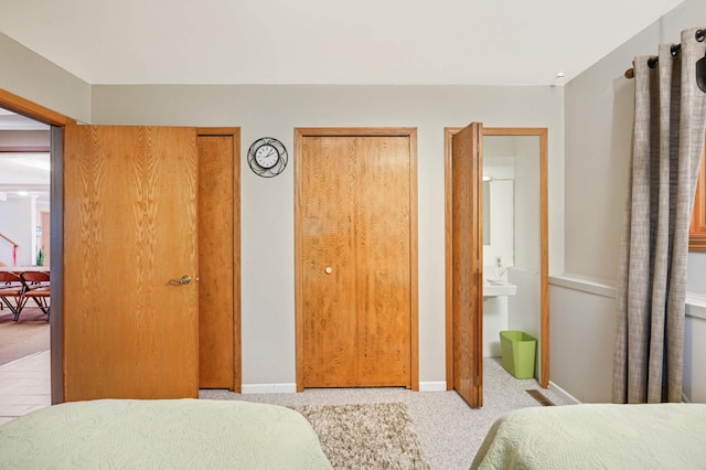 bedroom with light colored carpet, multiple closets, and ensuite bathroom