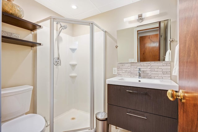 bathroom featuring backsplash, toilet, a shower with shower door, and vanity