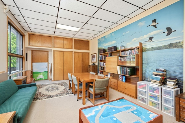 interior space with a paneled ceiling, a water view, and light carpet