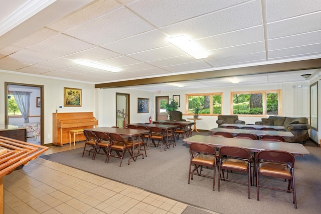 tiled dining area featuring a drop ceiling and ornamental molding