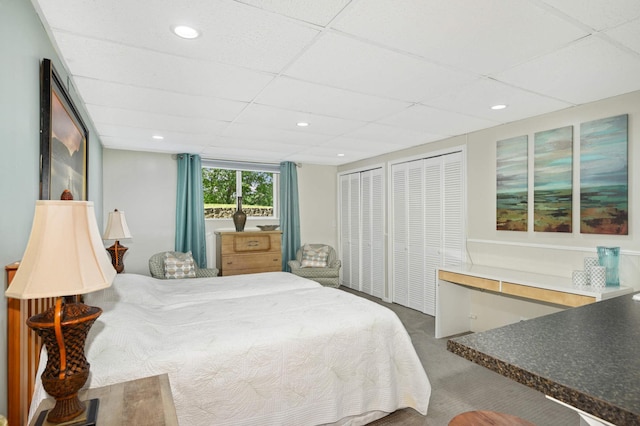 carpeted bedroom with two closets and a paneled ceiling