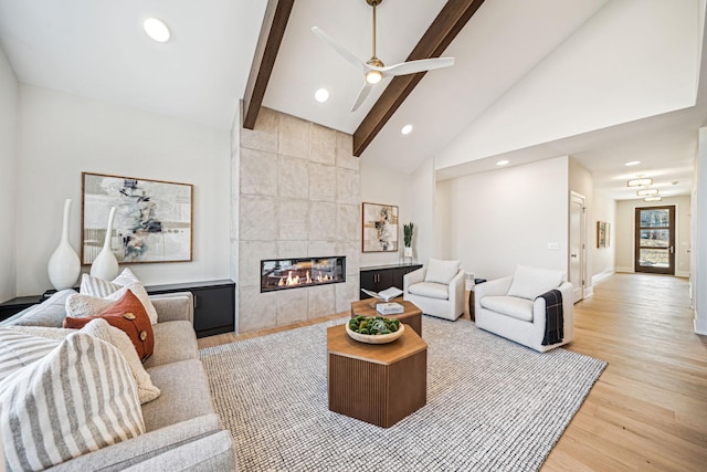 living room with a fireplace, light wood-type flooring, beam ceiling, tile walls, and ceiling fan