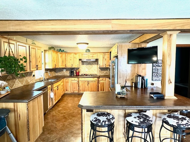 kitchen featuring sink, stainless steel appliances, tasteful backsplash, a textured ceiling, and decorative columns