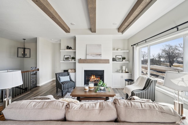 living room featuring built in shelves, a large fireplace, beamed ceiling, and dark wood-type flooring