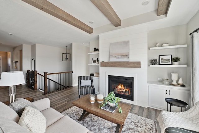 living room with built in shelves, a large fireplace, beamed ceiling, and dark hardwood / wood-style floors