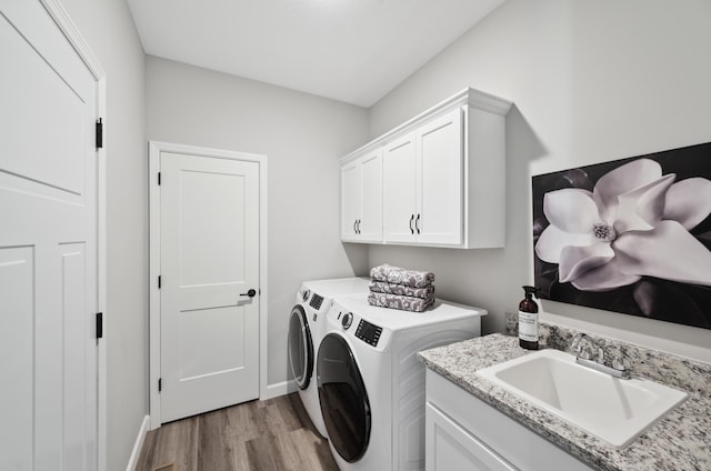 clothes washing area with cabinets, independent washer and dryer, light hardwood / wood-style floors, and sink