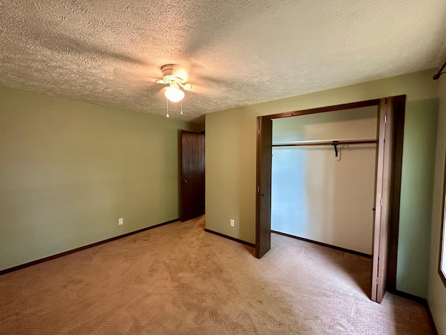 unfurnished bedroom featuring light carpet, a closet, ceiling fan, and a textured ceiling