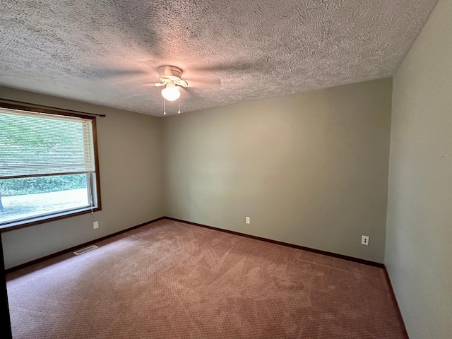 carpeted empty room featuring ceiling fan and a textured ceiling