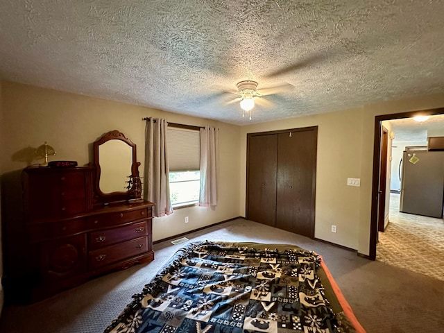 bedroom featuring ceiling fan, stainless steel fridge, a textured ceiling, a closet, and light carpet