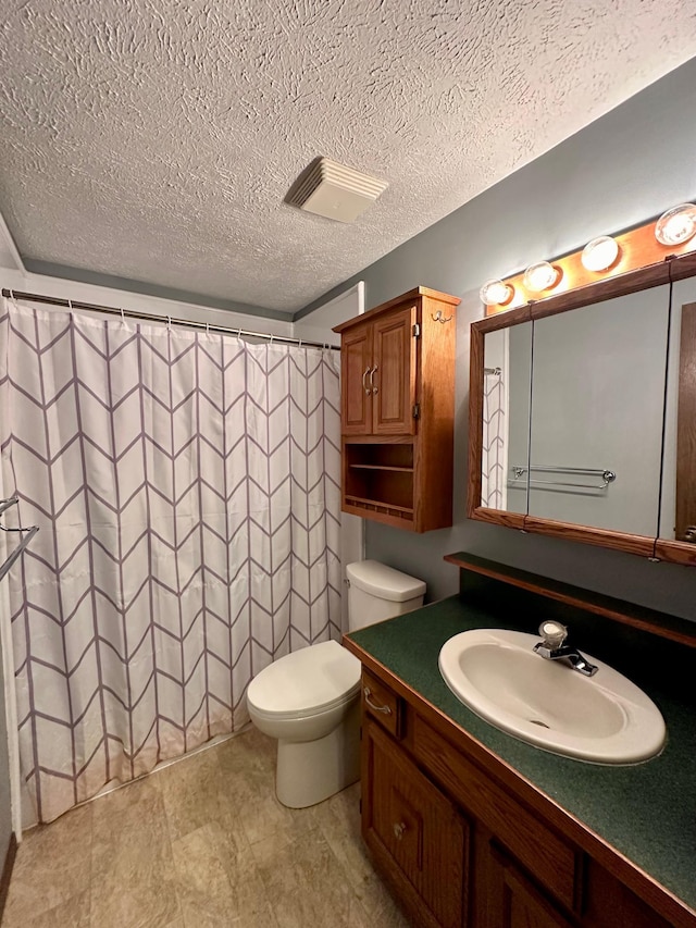 bathroom with vanity, toilet, a textured ceiling, and curtained shower