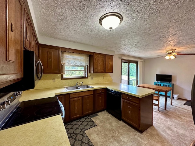 kitchen featuring black dishwasher, a textured ceiling, sink, stove, and kitchen peninsula