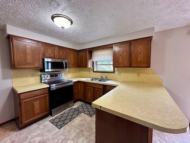 kitchen featuring stainless steel appliances, kitchen peninsula, a textured ceiling, and sink