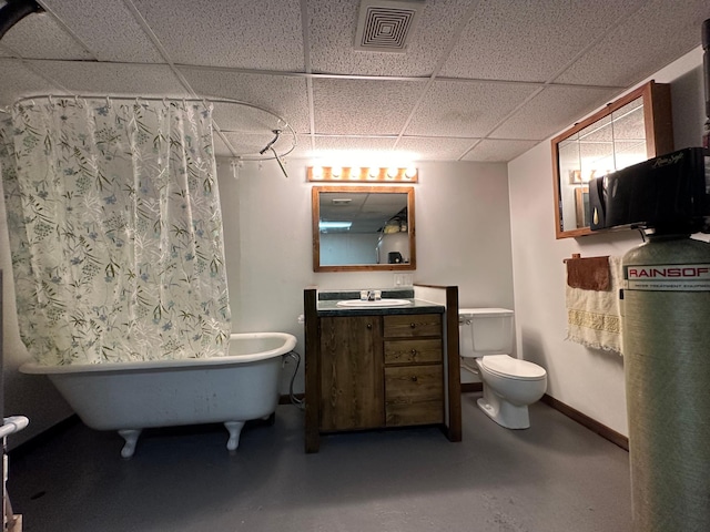 bathroom with a bath, a paneled ceiling, concrete flooring, vanity, and toilet