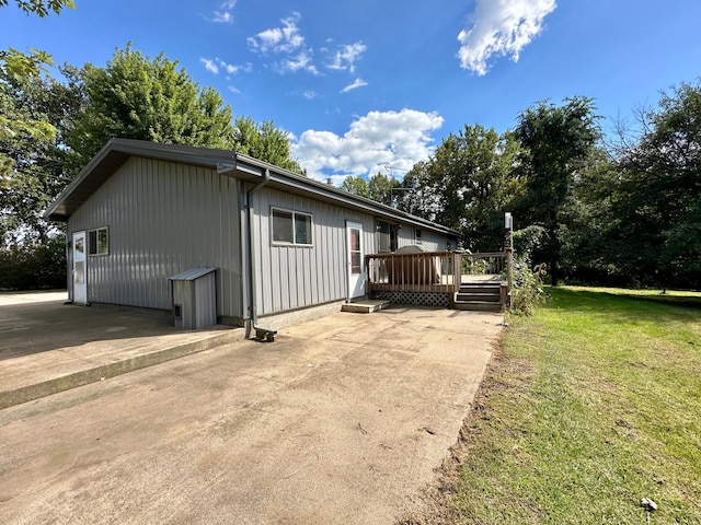 exterior space featuring a patio, a wooden deck, and a front yard