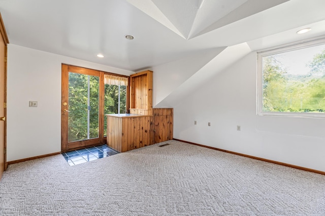 additional living space with a wealth of natural light, lofted ceiling, and light carpet