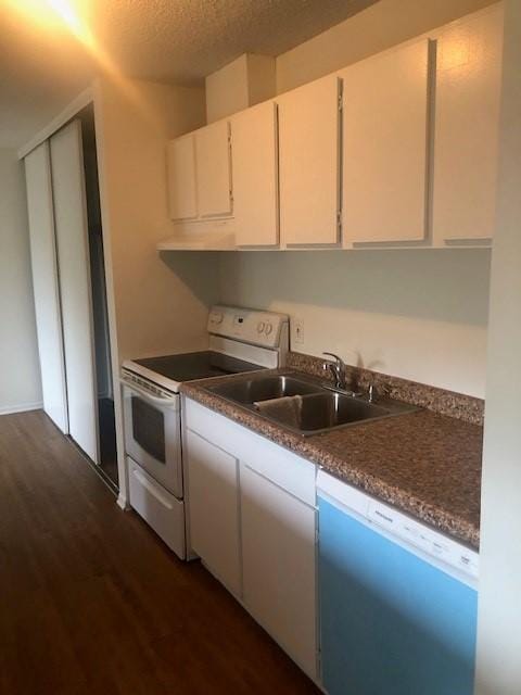 kitchen with sink, dark hardwood / wood-style flooring, white cabinetry, and white appliances