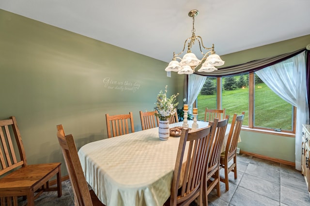 dining room with stone finish floor, a notable chandelier, and baseboards