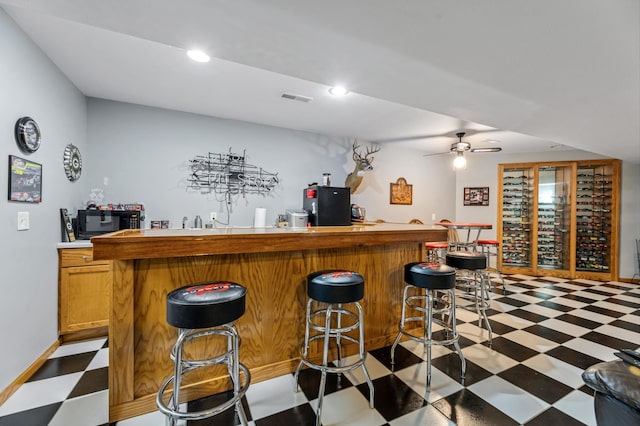 bar featuring tile patterned floors, visible vents, black appliances, and wet bar