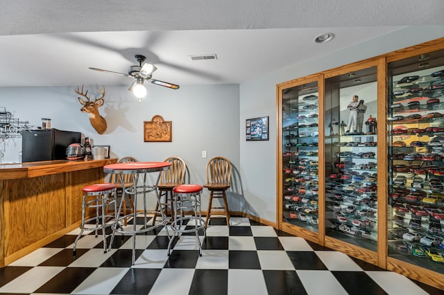 wine room featuring tile patterned floors, visible vents, a bar, and ceiling fan