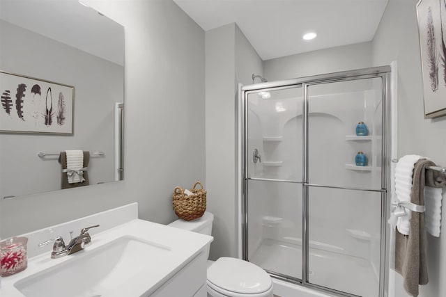 bathroom featuring vanity, a shower with door, and toilet