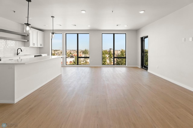 unfurnished living room with sink and light wood-type flooring